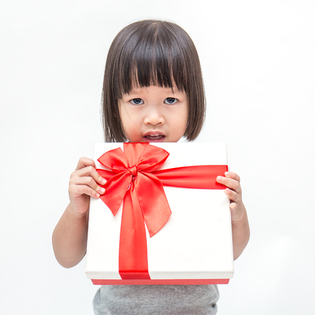 Portrait of little cute asian girl holding box of Christmas present, Small asian girl hug her gift with happy and fun expression isolated on white backgroundの写真素材