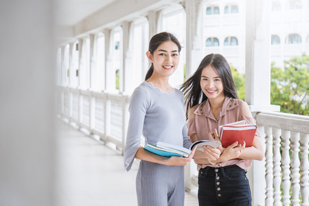 Asian student sitting outside school building reading book, Two asian girls reading book together. Education conceptの写真素材