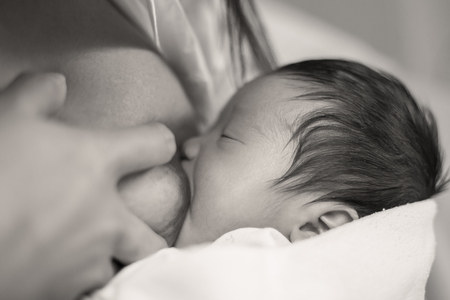 Newborn baby being breastfed just after deliveryの写真素材