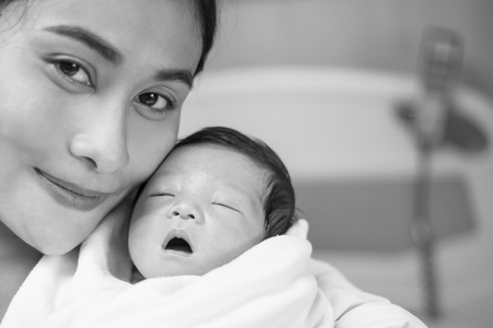 Portrait of beautiful young asian mother with her new born baby, copy space with bed in the hospital background.の写真素材