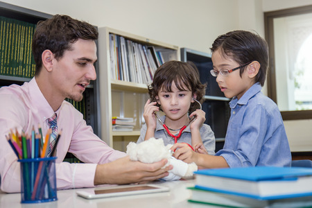 Teacher and students play doctor with stethoscope in the classroomの写真素材