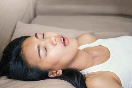 Beautiful young asian woman with attractive smile laying sleep on bed indoors. Portrait of woman in...
