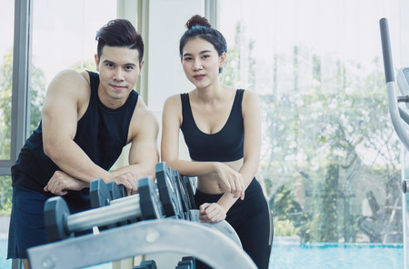 Woman with her personal fitness trainer in the gym, asian man and woman(couple) work out together at the gymの写真素材