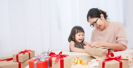 Asian little girl help her mother wrapping gift box, celebration holiday christmas motherâs day concept.の写真素材