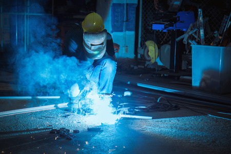 Worker while doing a welding with arc welder with the smoke, asian man wearing mask with his hands...