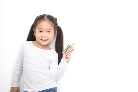 Portrait of cute little asian girl holding money isolated on white background. Small toddler asian girl counting her allowance dollar note.の写真素材