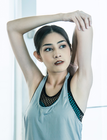 Portrait of asian fitness woman doing warm up exercises indoor, Close up Asian athlete woman stretching her arms at the gym. Healthcare conceptの写真素材