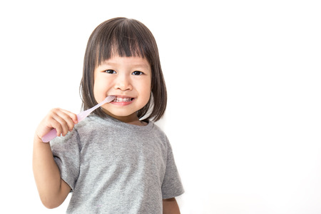 Portrait of young cute little toddler asian girl holding toothpaste brushing her teeth isolated on...