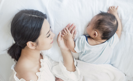 Close up portrait of beautiful young asian mother with her newborn baby, copy space with bed in the hospital background. Healthcare and medical love, lifestyle motherâs day conceptの写真素材