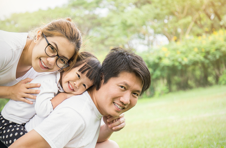 Portrait of happy family man woman and little girl playing outside. Young family of three having fun together outdoor. Asian parents and girl look happy and smile. Happiness and harmony in life.の写真素材