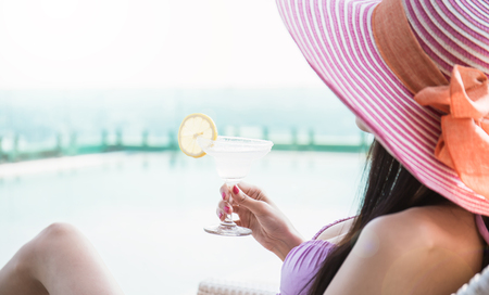 Beautiful asian female model drinking cocktail glass posing by the pool, outdoor portrait banner. Beach asian woman having fun in summer vacation holidays.  amazing style bikini, fashion girl in tropical weatherの写真素材