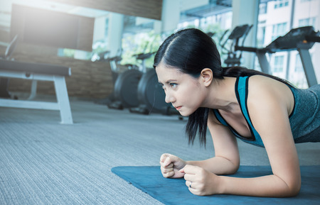 Gym asian crossfit woman working out doing push ups. Young mixed race fitness model training in...