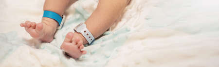 Closeup feet of newborn baby with tag on the legs in hospital bed. Healthcare and medical love lifestyle father or motherâs day background concept bannerの写真素材