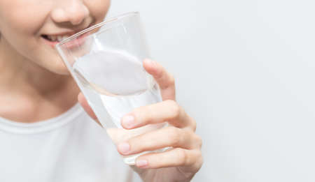 Close up portrait of beautiful asian woman drinking glass of water isolated on white background....