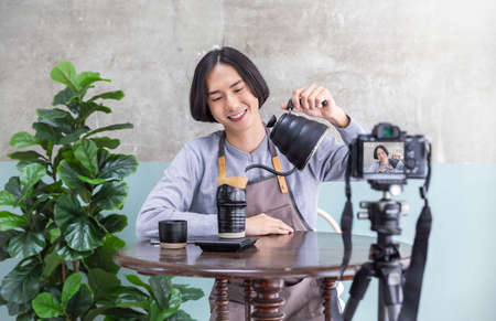 Startup successful small business owner sme handsome vlogger boy video online marketing with camera in cafe. Portrait young asian man barista cafe owner. SME entrepreneur blogger business conceptの写真素材