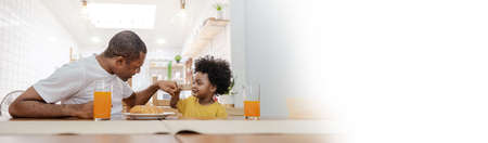 Portrait of happy African american father and son hands fist bump during breakfast time at dining table with copy space. Single dad family love lifestyle, fatherâs day panoramic bannerの写真素材