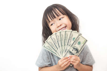 Portrait of cute little asian girl holding money isolated on white background. Small toddler asian girl counting her allowance dollar note.の写真素材