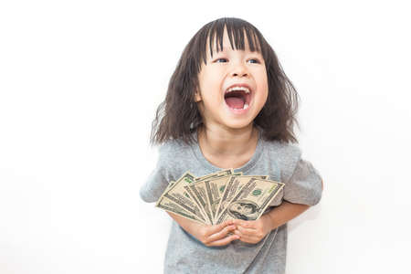 Portrait of cute little asian girl holding money isolated on white background. Small toddler asian girl counting her allowance dollar note.の写真素材