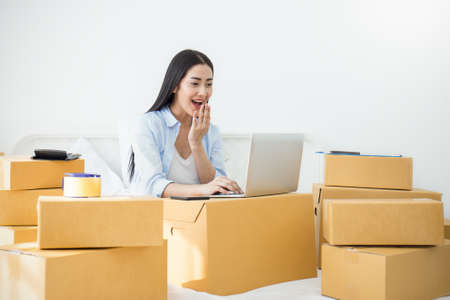 Startup small business entrepreneur SME freelance woman working at home office , Young Asian small business owner using computer, online marketing packing box delivery, SME e-commerce telemarket conceptの写真素材