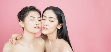 Closeup portrait of two young beautiful sexy asian woman isolated on pink background. Beauty healthy...