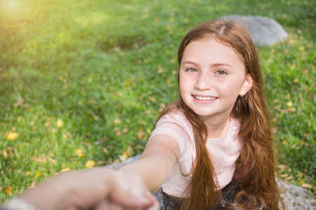 Closeup little girl holding her mother or fatherâs hand leading on green meadow field nature outdoor. Nature love family holiday travel conceptの写真素材