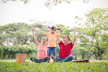 Portrait of happy family man woman and little girl playing outside. Young family of three having fun...