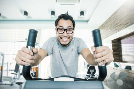 Attractive young asian nerd man runs on a treadmill air walk, asian handsome boy is engaged in fitness sport club, healthcare and medical conceptの写真素材