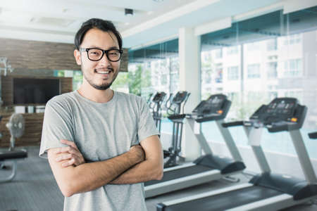 Portrait of Asian young handsome nerd man with arm crossed at fitness, asian man workout  at the gym sport club, healthcare and medical conceptの写真素材
