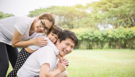 Portrait of family man woman and little girl playing outside. Young asian family having fun picnic outdoor. Happy smile Asian parents and daughter. Happiness harmony activities summer or spring together lifestyle concept bannerの写真素材
