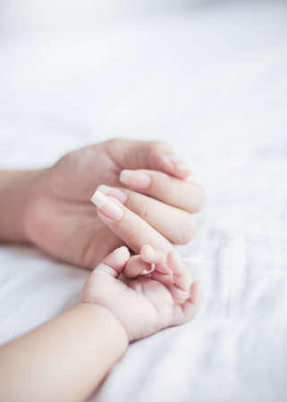 Asian parent hands holding newborn baby fingers, Close up motherâs hand holding their new born baby. Love family healthcare and medical motherâs day conceptの写真素材