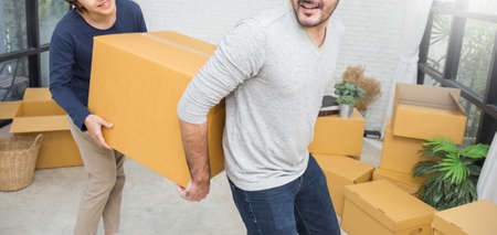 Young interracial couple man and woman help carry box move to new house. Happy just married couple with pile of boxes. Startup moving new diversity family love together teamwork lifestyle concept bannerの写真素材