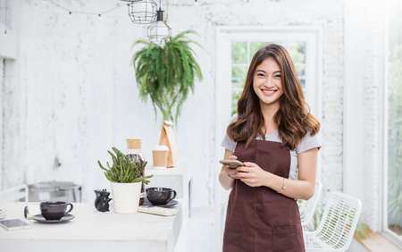 Startup successful small business owner beauty girl standing with arms crossed in coffee shop or restaurant. Portrait of young asian tan woman barista cafe owner. SME entrepreneur business conceptの写真素材