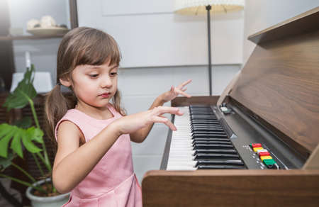 Portrait of little cute caucasian pianist girl playing piano song, preschool music talent gifted, musical class school learning by doing education leisure conceptの写真素材