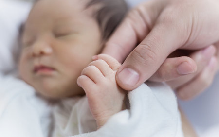 Asian parent hands holding newborn baby fingers, Closeup motherâs hand holding their new born baby. Together love family nursery healthcare and medical fatherâs day conceptの写真素材