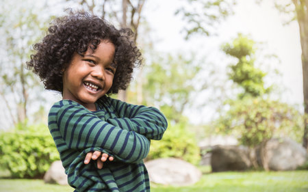 Fun in the spring park. Portrait of young happy black boy stand on green grass background. Education back to school spend leisure time in nature forest conceptの写真素材