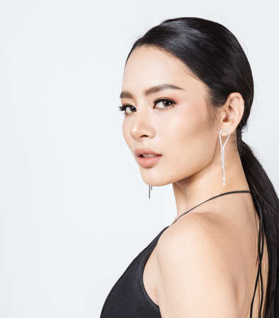 Closeup portrait young beauty asian model fashion girl with diamond earrings black dress. Beautiful face of clean fresh perfect skin woman. Facial treatment makeup cosmetic health care makeup party conceptの写真素材