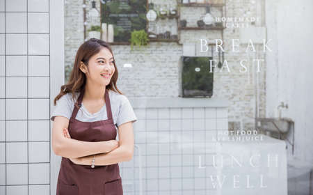 Startup successful small business owner sme beauty girl standing with arms crossed in coffee shop or restaurant. Portrait of young asian tan woman barista cafe owner. SME entrepreneur business conceptの写真素材