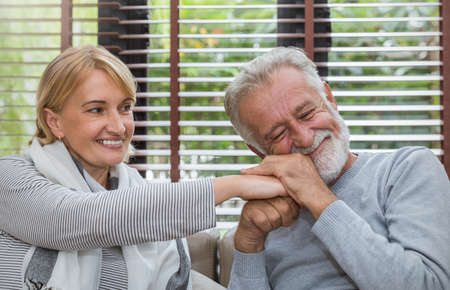Happy old couple smiling on couch in living room, caucasian senior couple relax at home in cold winter season. Healthcare family together lifestyle retirement valentinesâ day conceptの写真素材