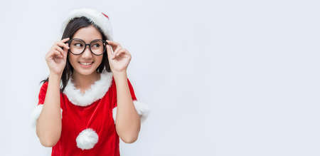 Portrait of asian beautiful nerd woman wearing santa custume. Smiling happy asian girl wear glasses isolated on white copy space background. Christmas party and holiday concept panoramic bannerの写真素材