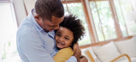 Portrait of american african black father and son hugging laughing in living room. Happy daddy and his little boy spending leisure time at home. Single dad, family lifestyle father's day conceptの写真素材