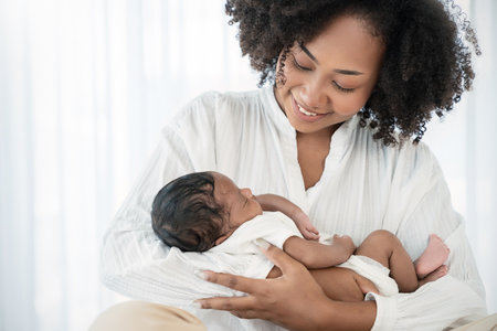 Close up portrait of beautiful young African American  mother holding sleep newborn baby in hospital bed room. Healthcare medical love black afro woman lifestyle mother's day, breast with copy space.の写真素材