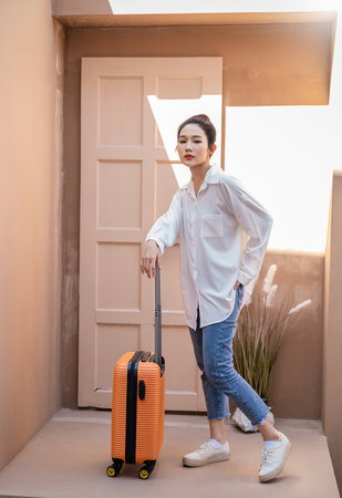 Portrait young beautiful asian woman traveler stand hold suitcase full body on holiday vacation summer time. Happy cheerful asian girl solo travel in summer. Korean University woman fashion lifestyle.の写真素材