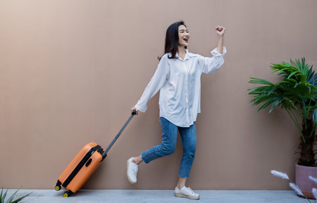 Portrait young beautiful asian woman traveler stand hold suitcase full body on holiday vacation summer time. Happy cheerful asian girl solo travel in summer. Korean University woman fashion lifestyle.の写真素材