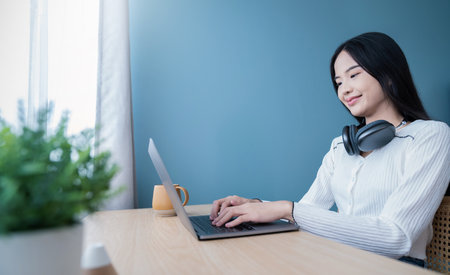 Portrait of nerd sme business asian woman work from home at headphone online computer desktop table Beauty Asia freelancer girl using laptop in bed room. Small business sme digital network, technologyの写真素材