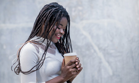 Portrait of beautiful African American successful business girl with copy space on street background sip on coffee or tea from sustain brown paper take away to go cup. Education modern lifestyle.の写真素材