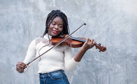 Portrait smile confident teenager long hair black woman play violin on street. Education music instrument  modern minimal style.の写真素材