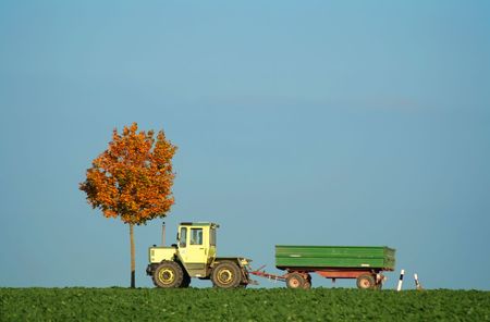 tractor driving along field in autumnの写真素材