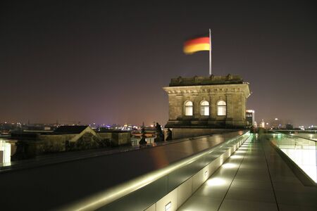 flag flying above reichstag tower at night, berlin, germanyの写真素材