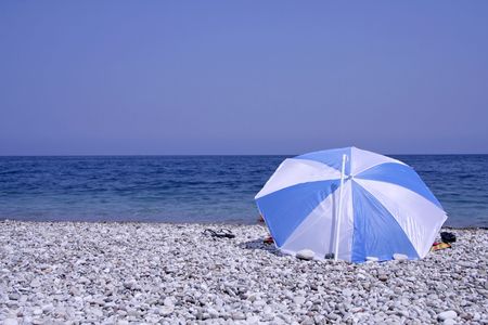 blue and white striped parasol on beachの写真素材