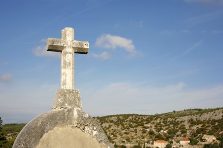 white stone cross on blue sky and cloudy backgroundの写真素材